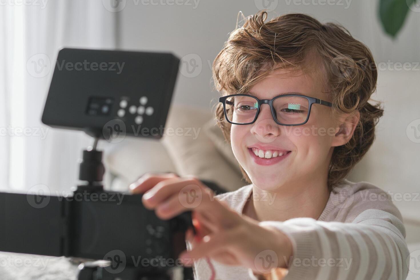 Positive boy setting up camera while recording for blog photo