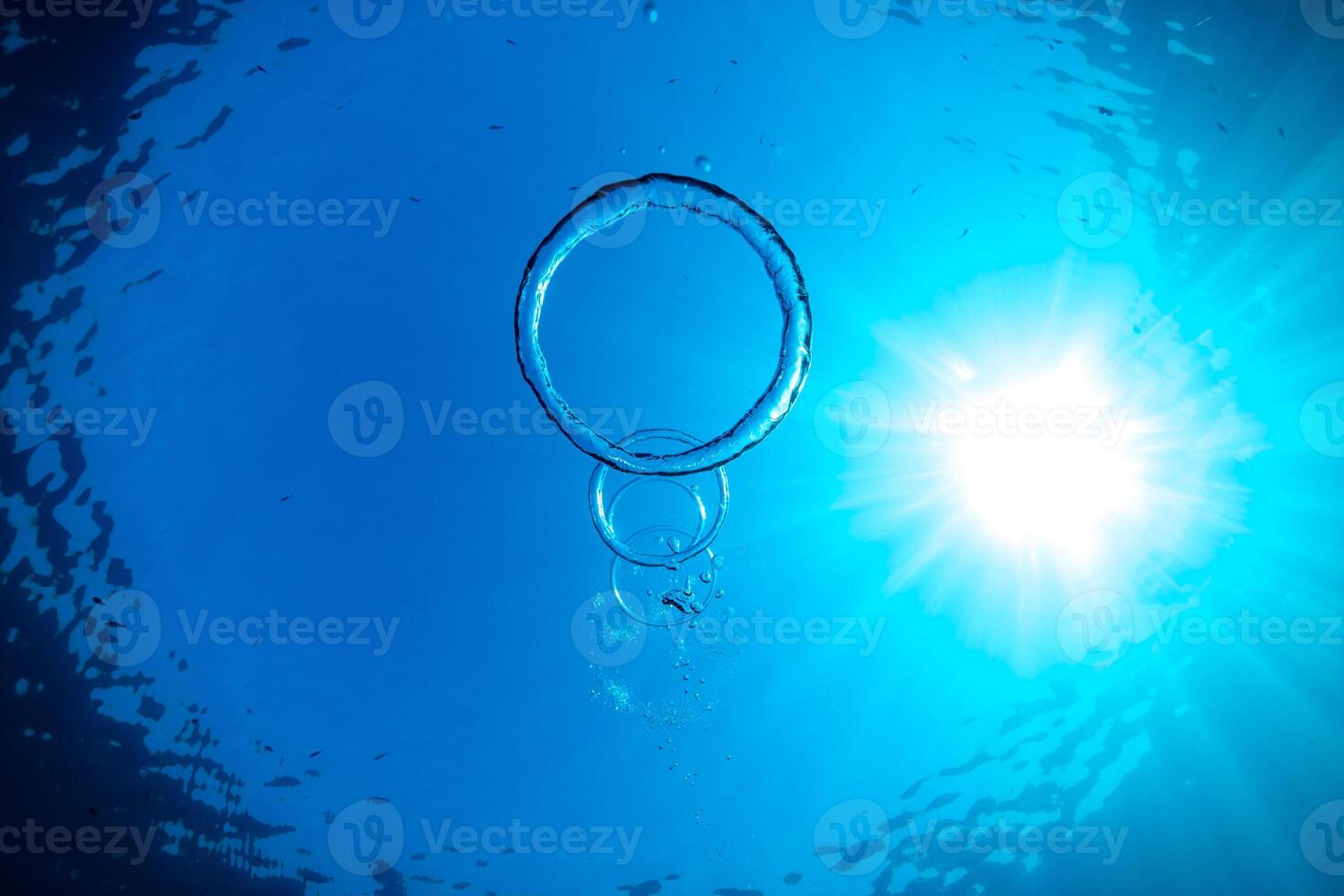 Toroidal bubbles under blue sea water in sunlight photo