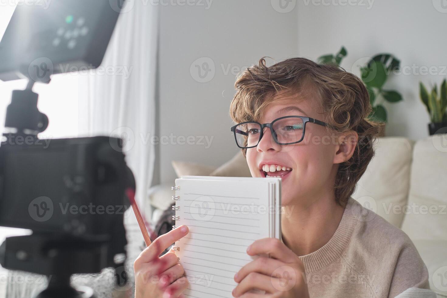 Smart positive boy in glasses recording on camera at home photo