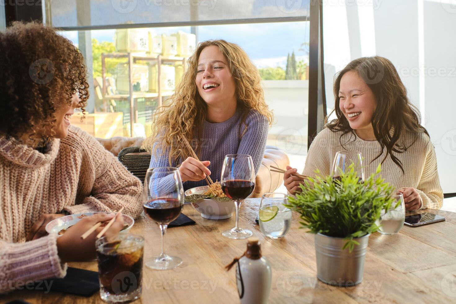 Happy multiracial females chatting during lunch in cafe photo