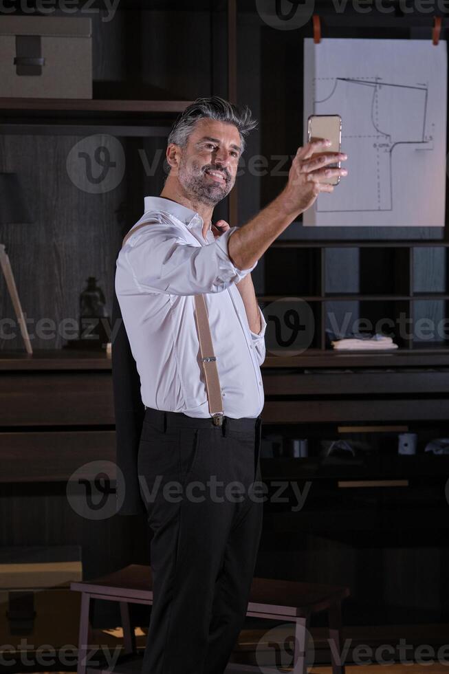 Mature elegant businessman taking selfie in wardrobe photo