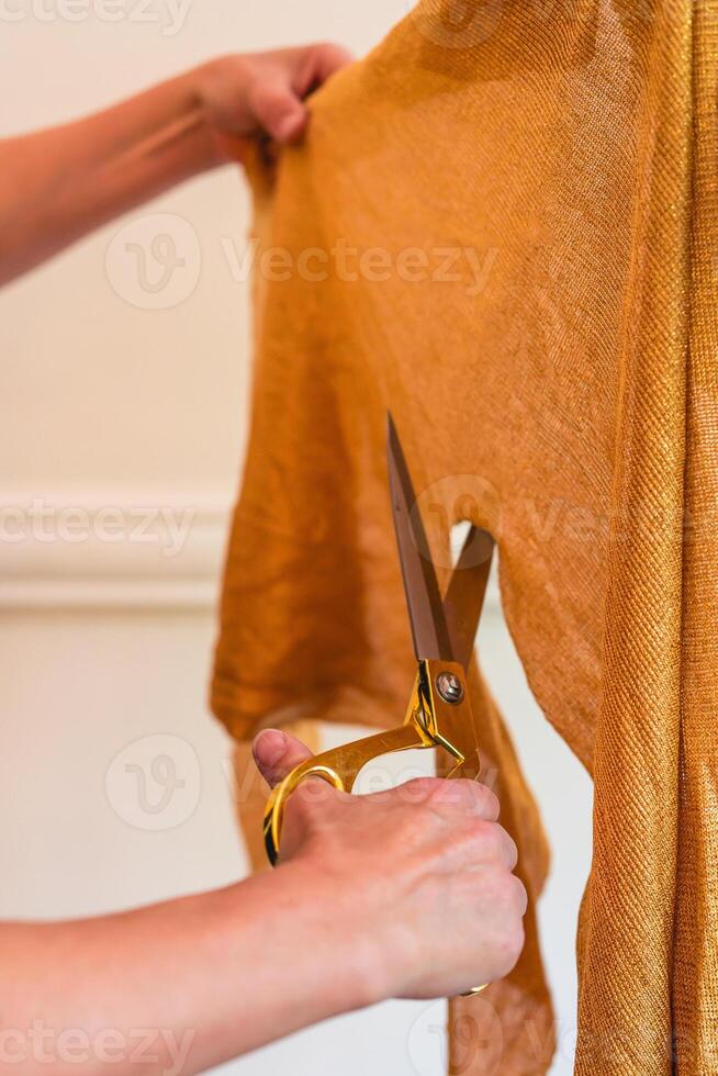 Close-up of fashion designer hands using textile scissors to work on clothing design. Vertical shot photo