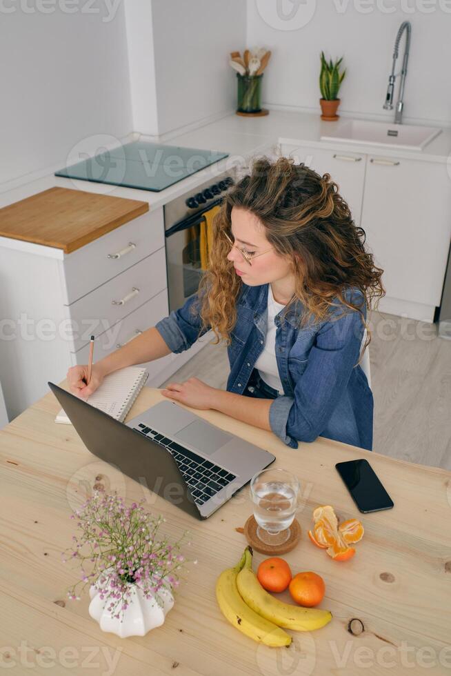 Female entrepreneur taking notes in notebook at home photo