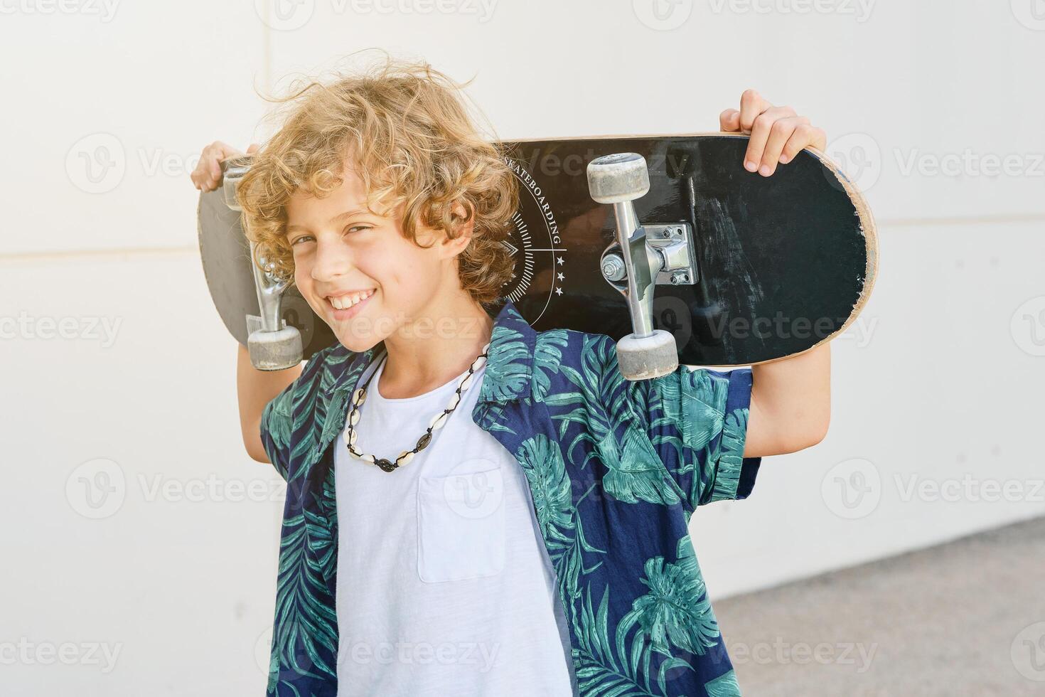 Cheerful boy with skateboard on neck photo