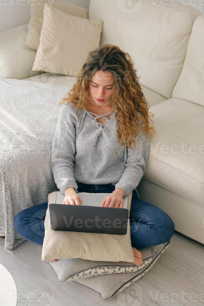 Young woman with notebook sitting on pillow photo