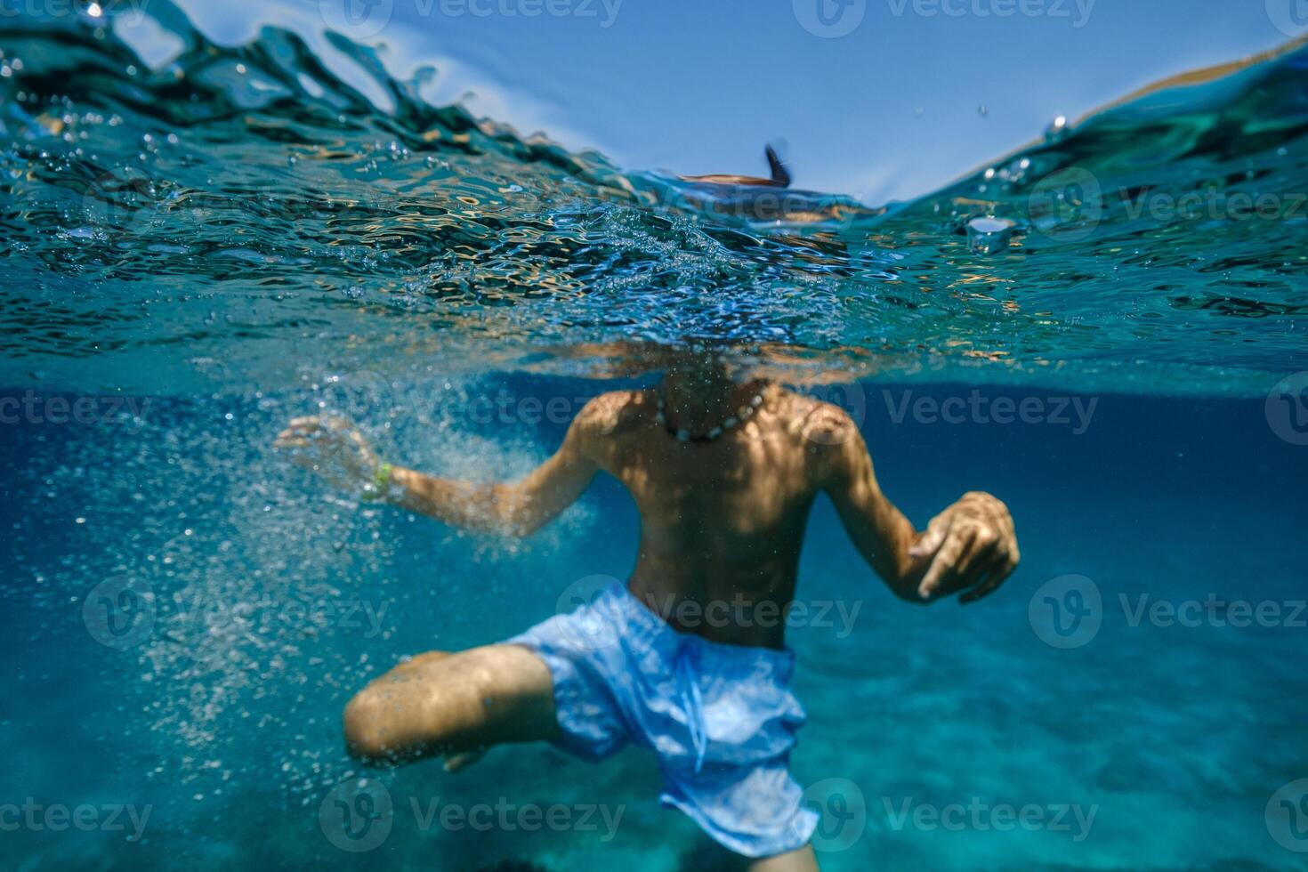Unrecognizable kid swimming in sea photo