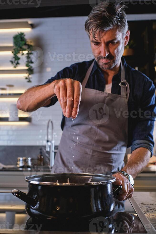 Man salting food in saucepan photo