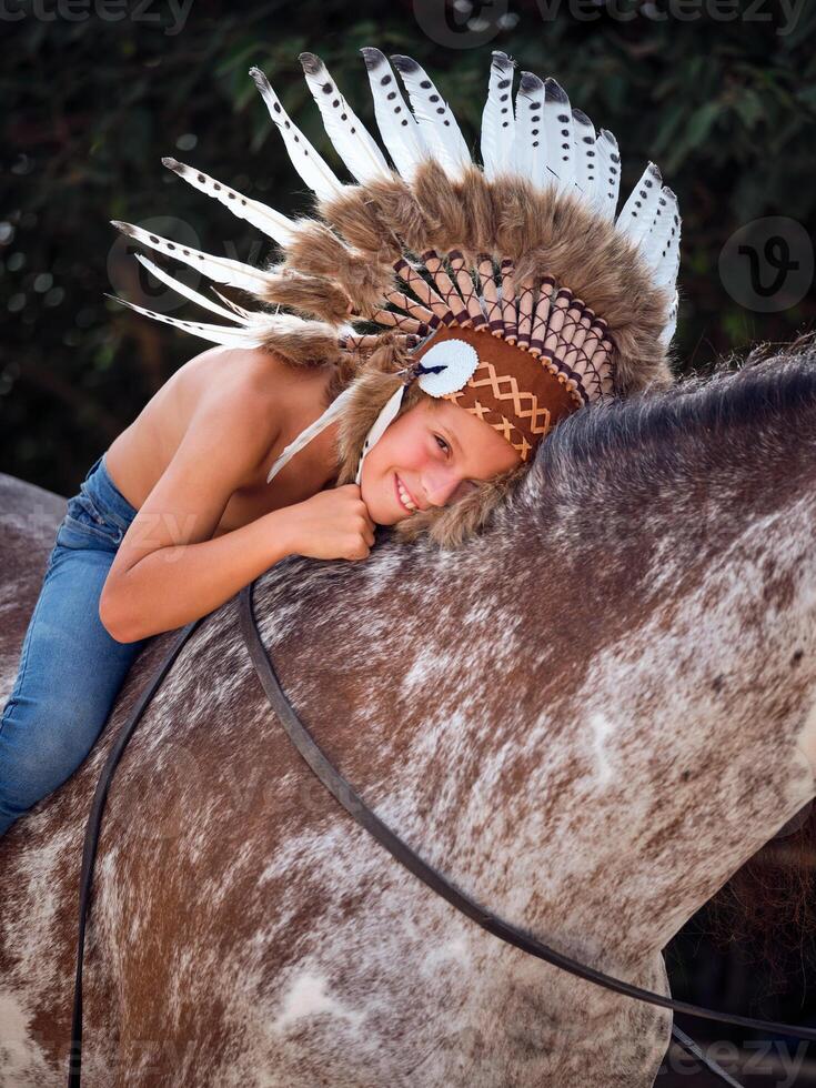 Young smiling boy hugging horse while sitting on with reins photo