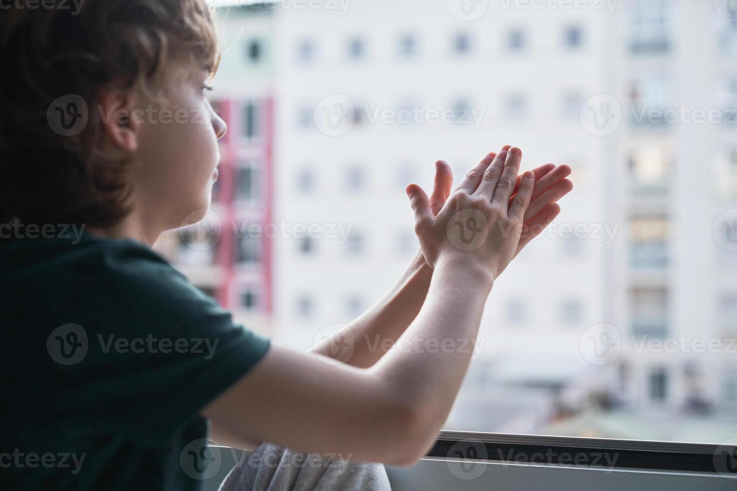 Boy staring out window and clapping hands photo