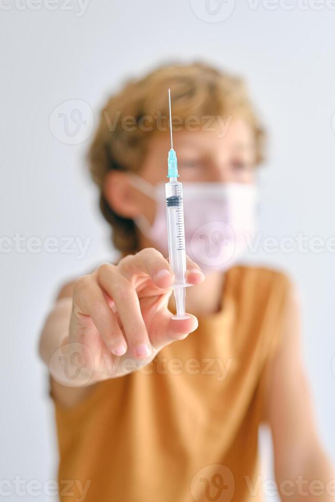 Boy in mask with vaccine in syringe photo