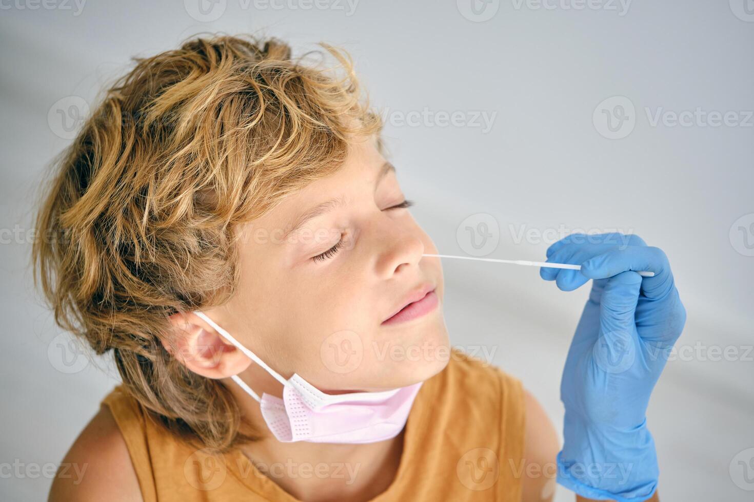 Crop nurse taking COVID test from boy in clinic photo