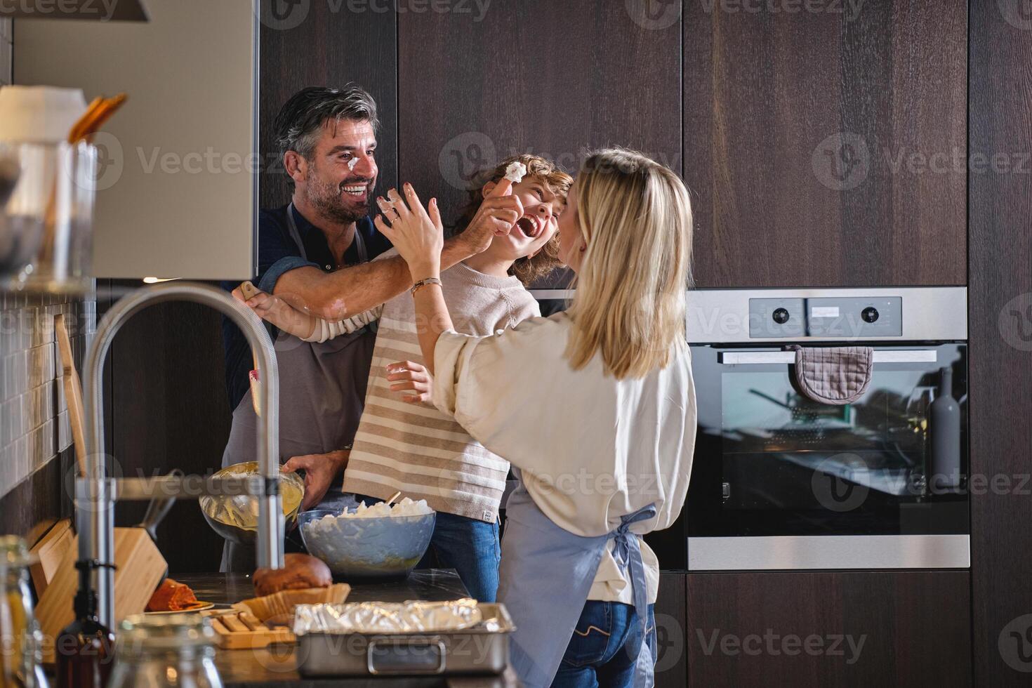 Happy family throwing dough at one other while baking at home photo