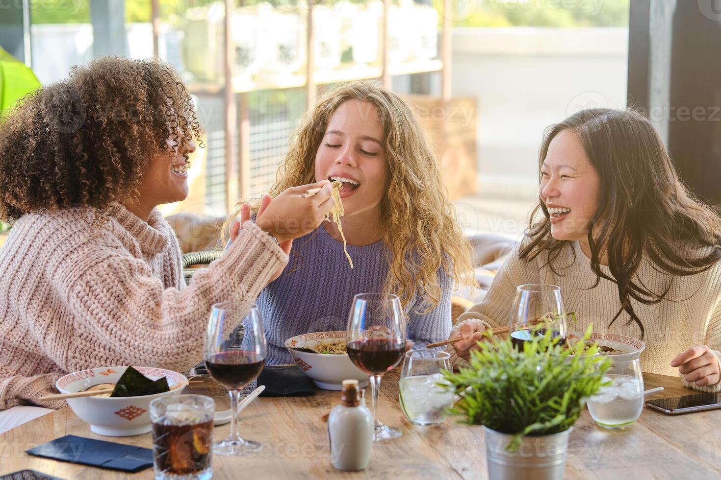 Diverse women having fun while eating ramen in restaurant photo