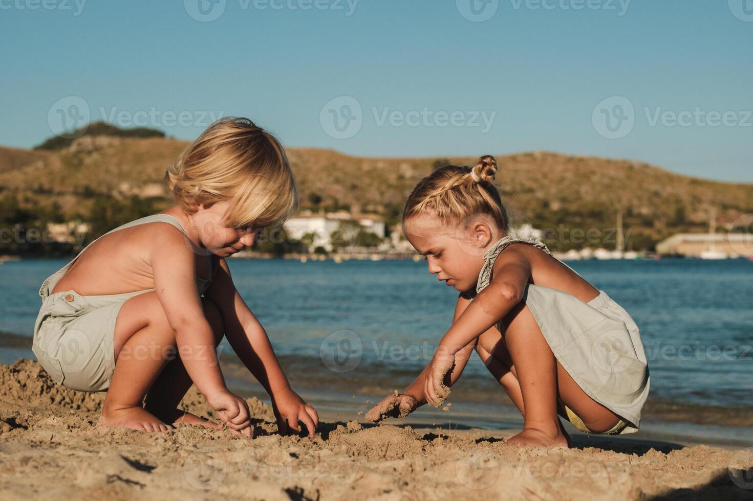 Concentrated kids playing with sand near lake photo