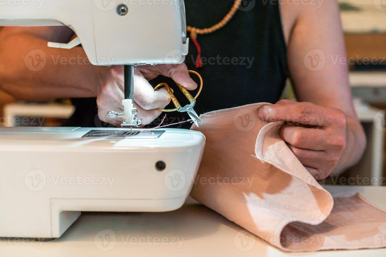 Close up pf woman cutting a thread while working with a sewing machine photo