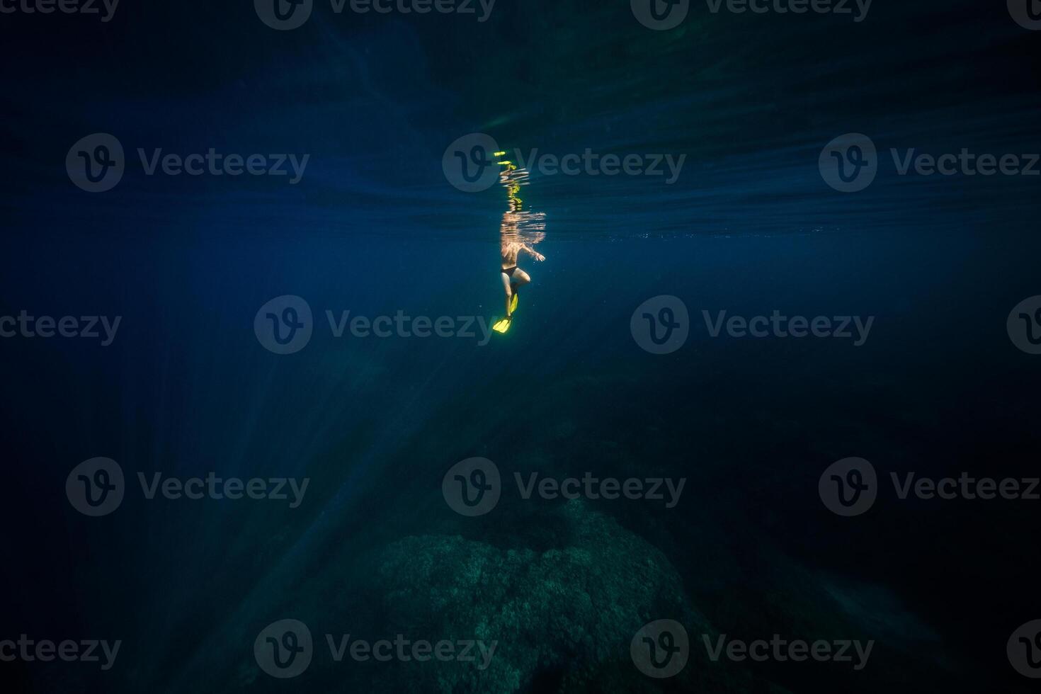 Anonymous man diving in deep blue ocean photo
