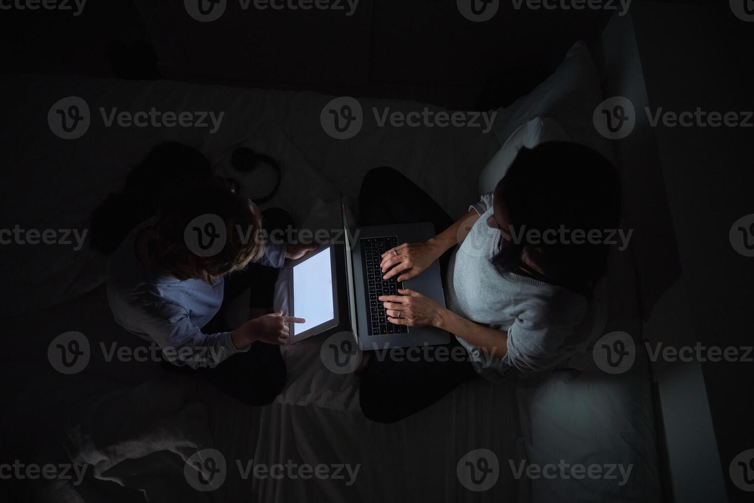 Mother with son browsing gadgets while doing homework in darknes photo