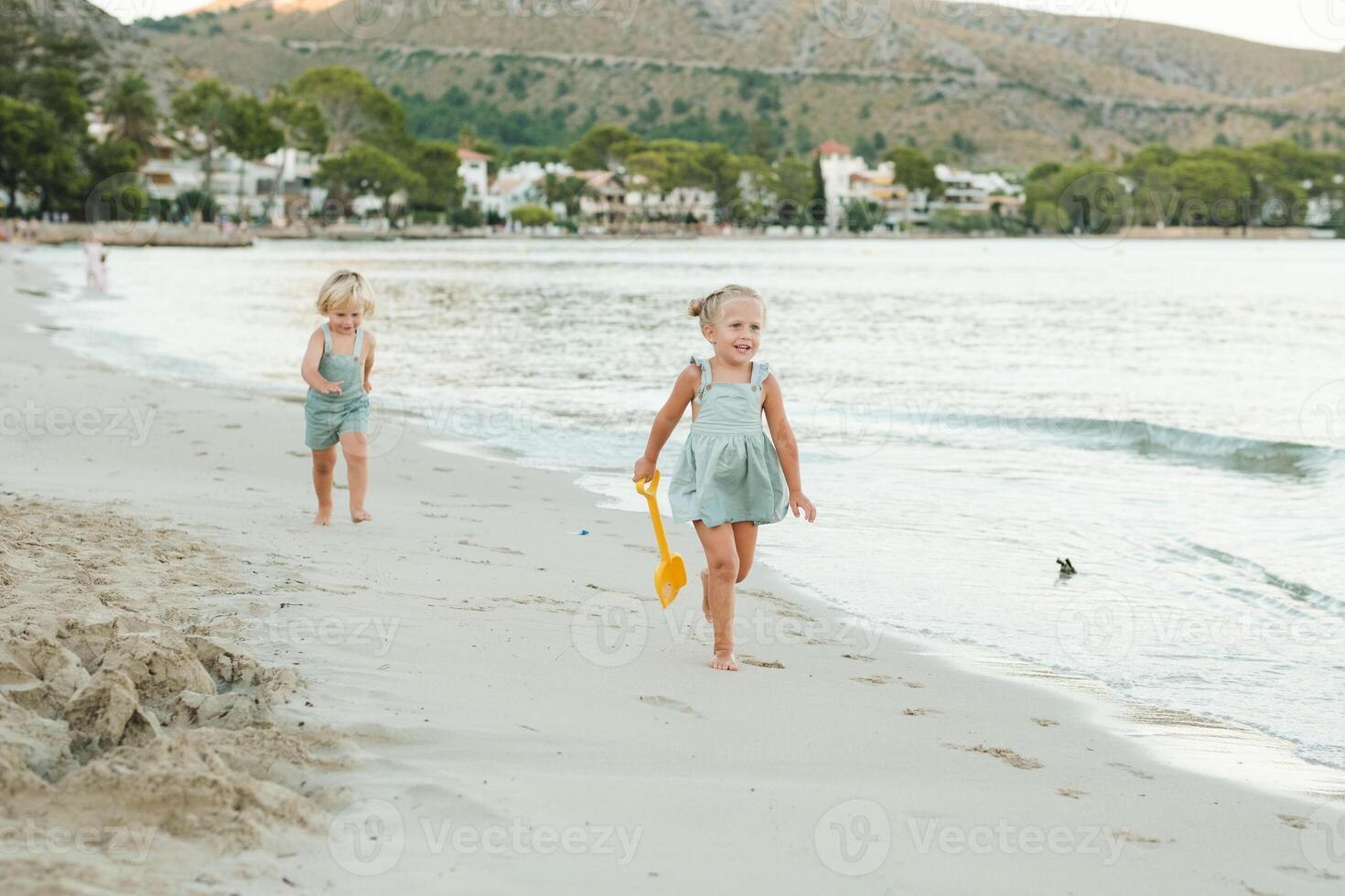 Little brother and sister walking on seaside in sunshine photo