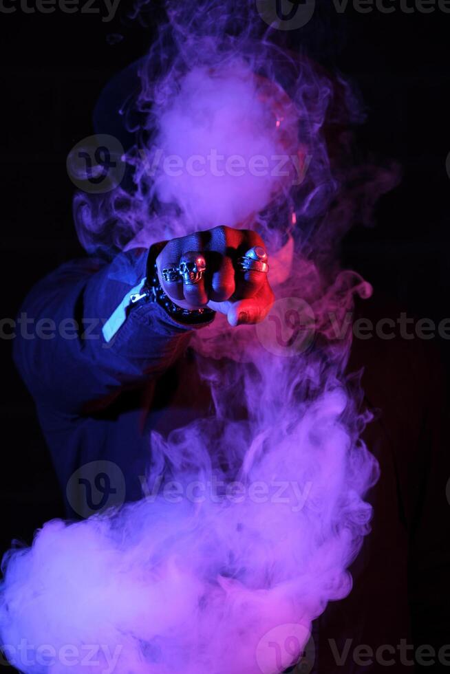 Unrecognizable man surrounded by smoke in neon lighting photo