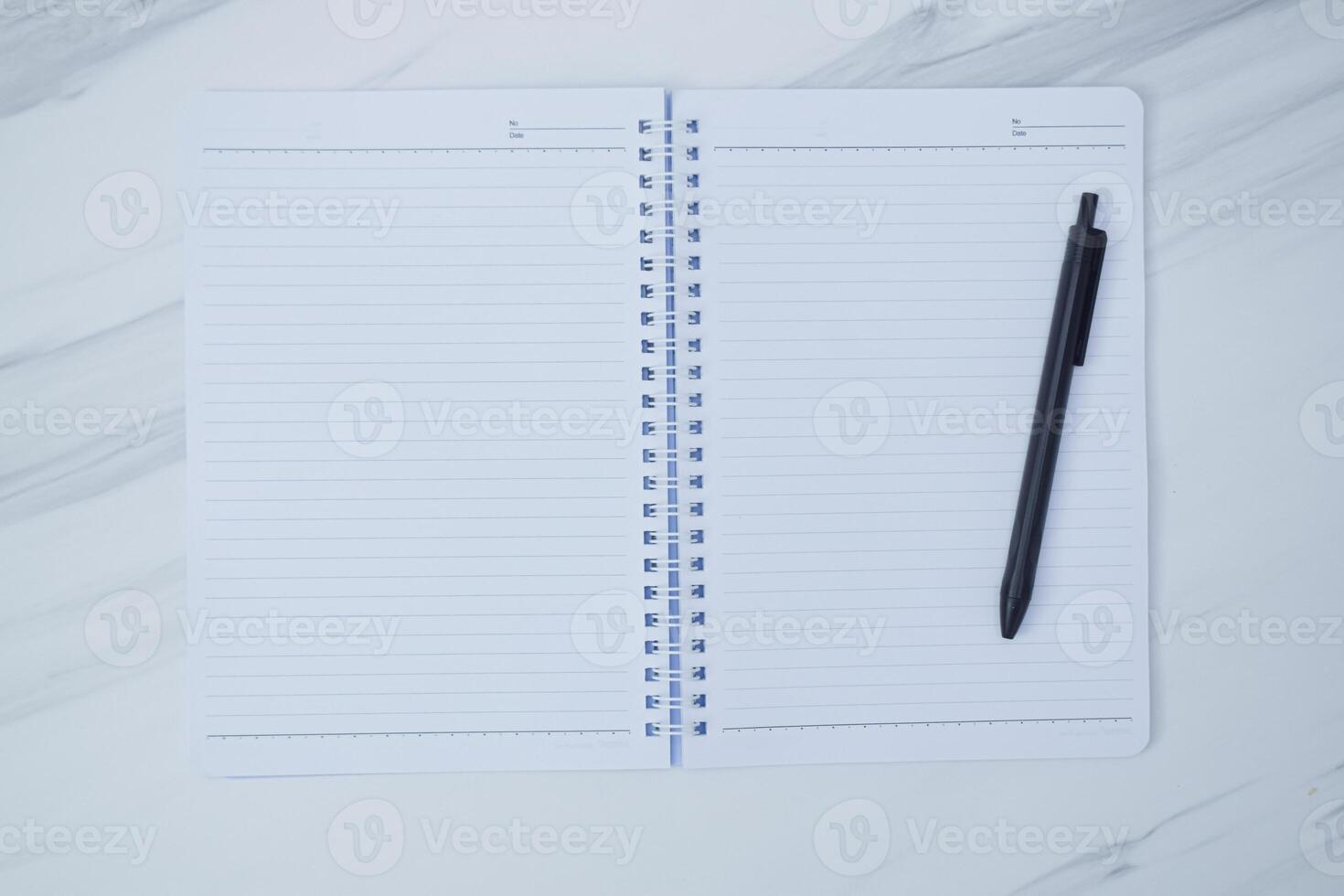 An open notebook and a black pen are displayed on a surface photo