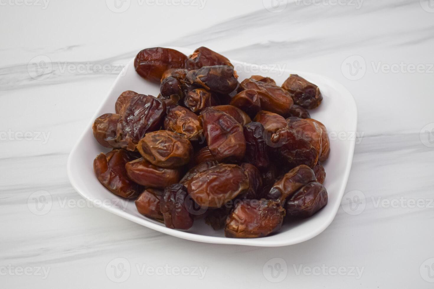 Fresh Dates Are Arranged Nicely In A White Square Dish photo
