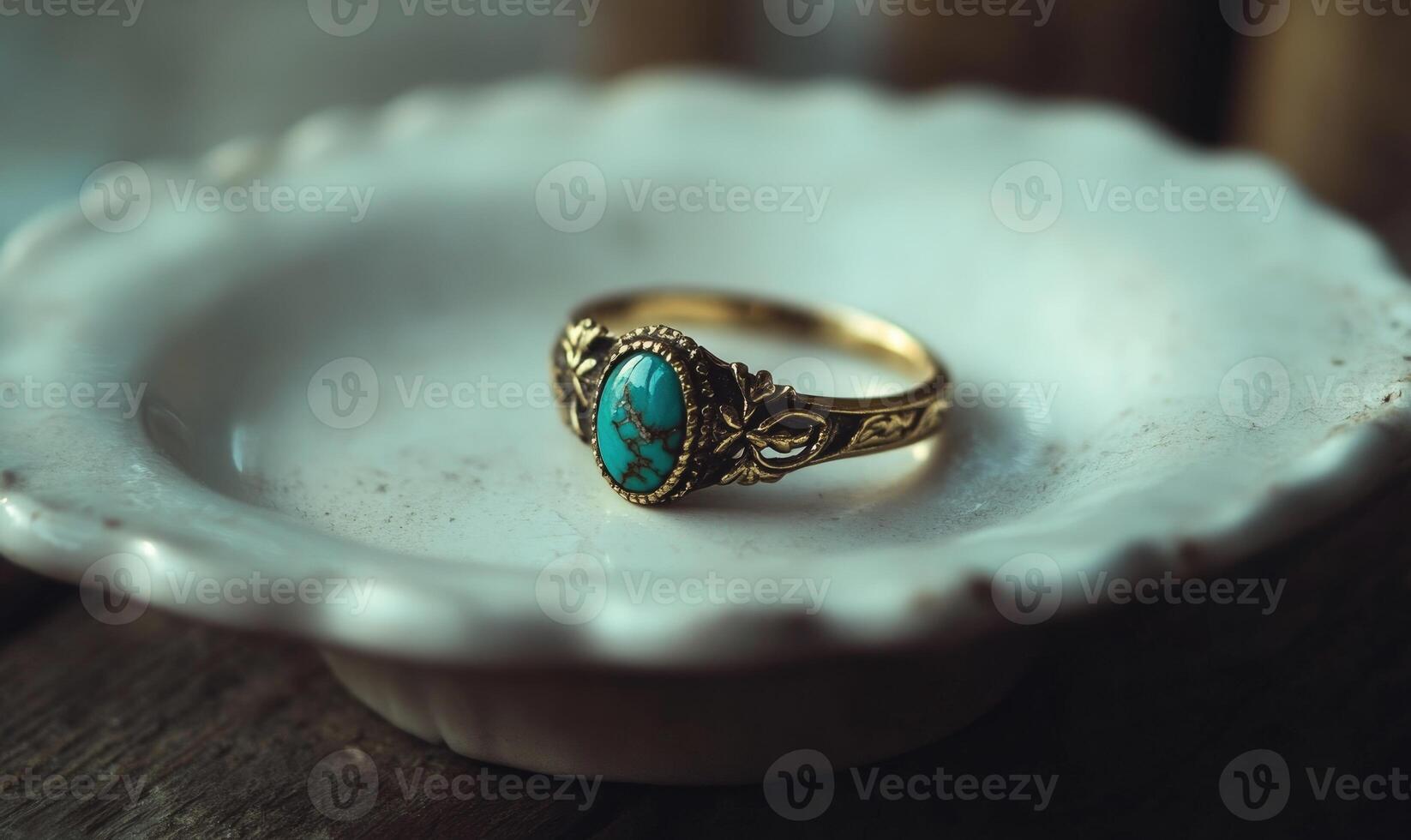 A gold and turquoise ring is sitting on a white plate photo