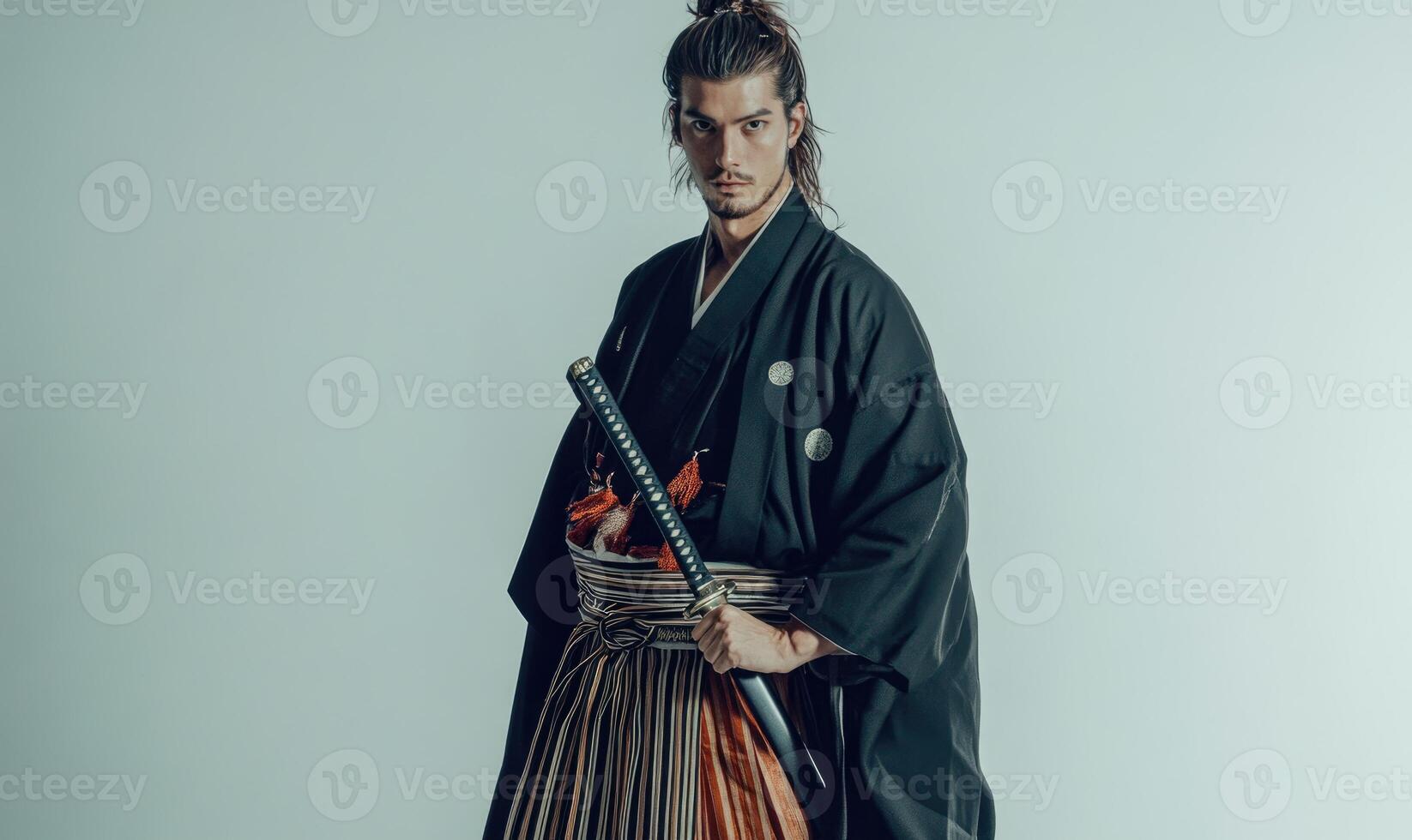 A man in a black kimono is holding a sword photo
