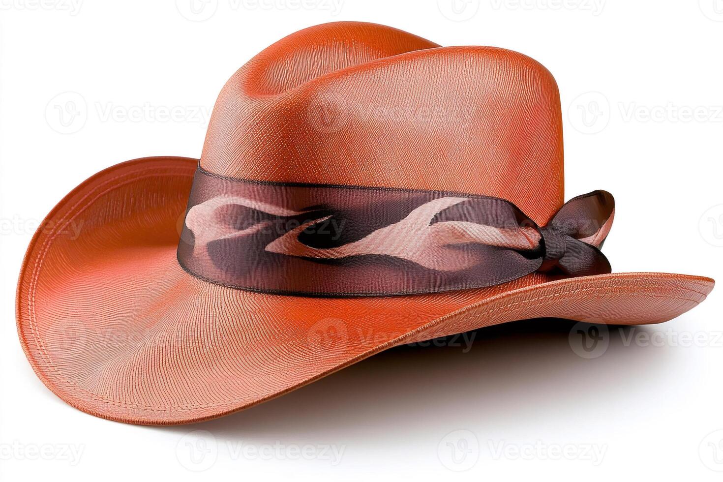 Orange cowboy hat with decorative ribbon resting on white background photo
