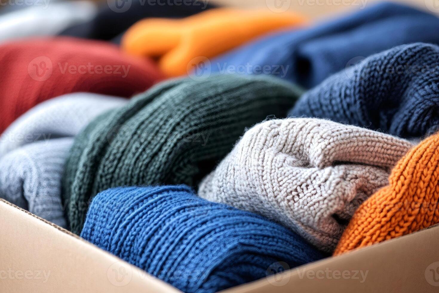 Colorful knitted sweaters are neatly folded and stored in a cardboard box photo