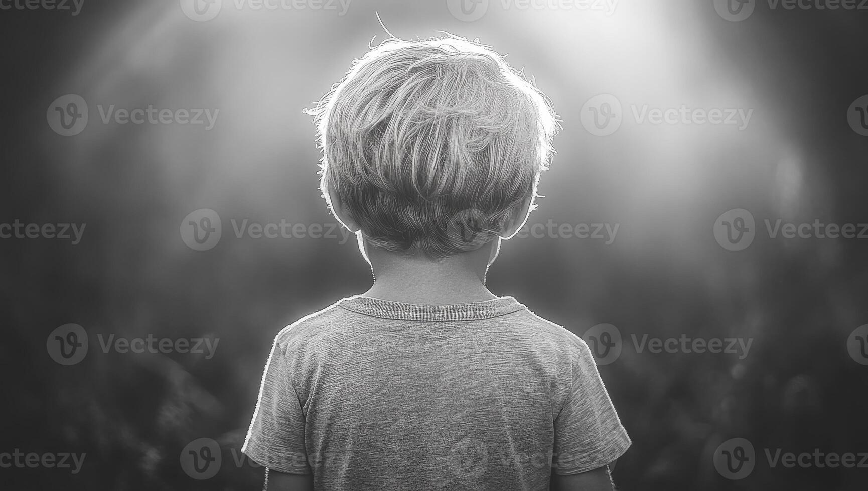 Child gazing into the distance in nature. A young child with tousled hair stands alone, looking at the bright expanse before him in the soft light of dusk. photo