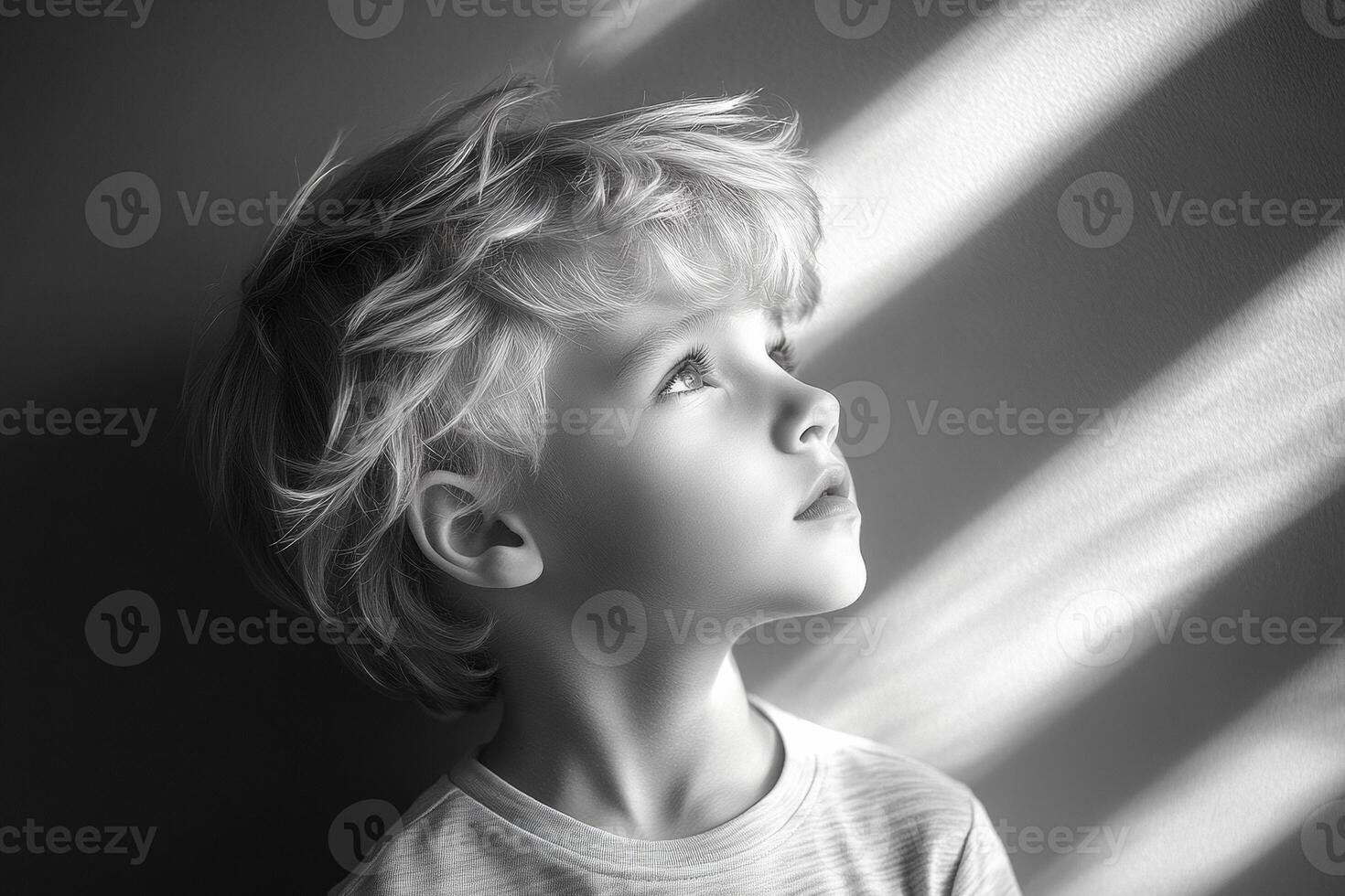 Young boy gazes thoughtfully at light. A young boy with curly hair is looking up thoughtfully, captivated by the play of light on the wall. photo