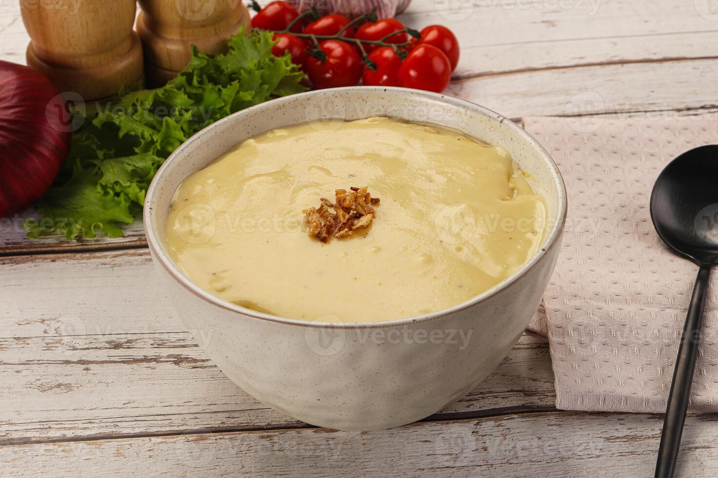 A bowl of soup with a spoon and some vegetables photo