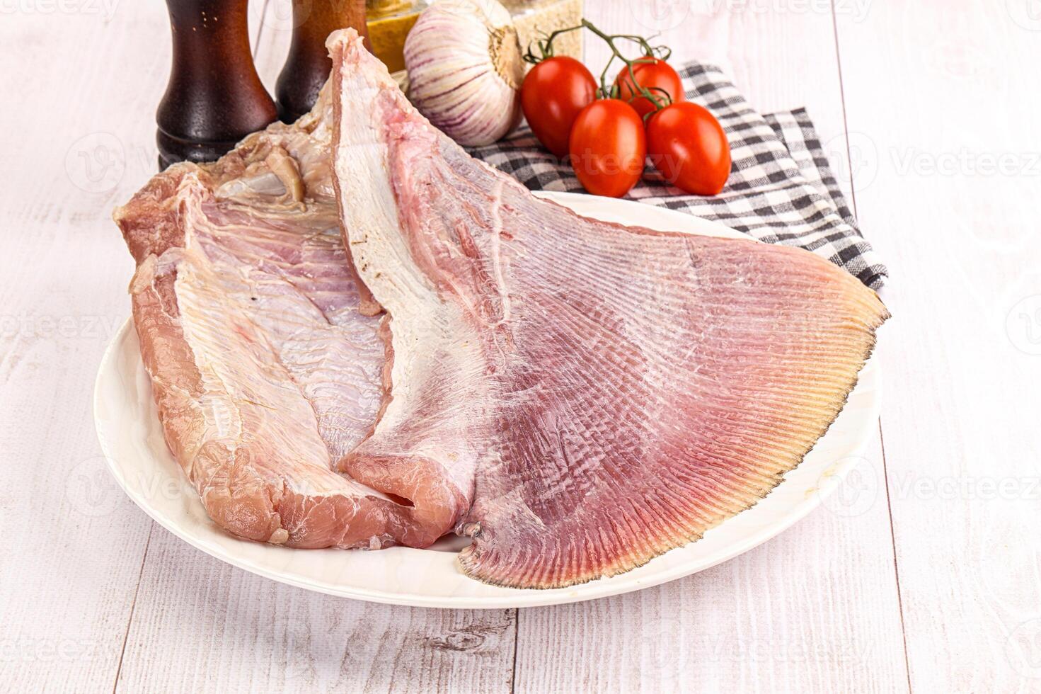 Raw fish on a plate with tomatoes and garlic photo