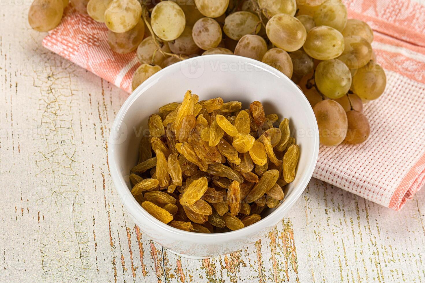 A bowl of raisins and a bunch of grapes photo