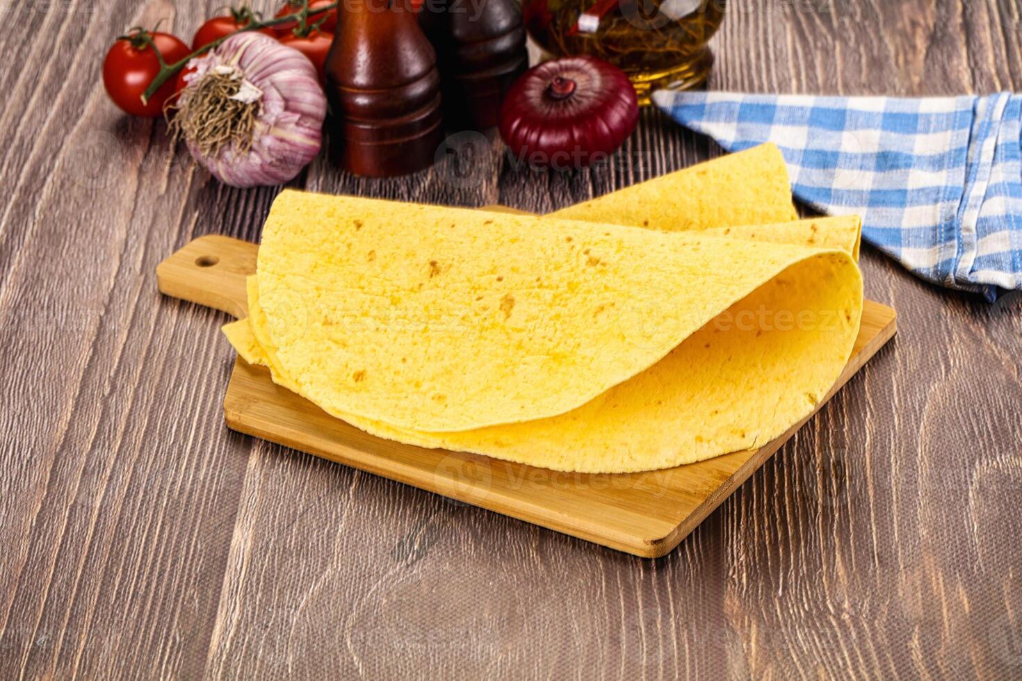 A tortilla on a cutting board with tomatoes and spices photo