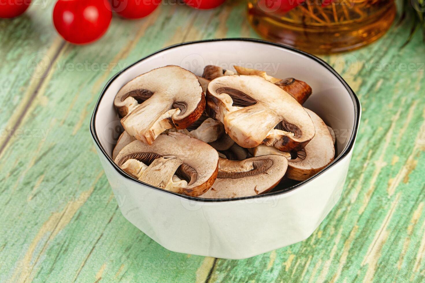 A bowl of mushrooms on a table with a bottle of wine photo