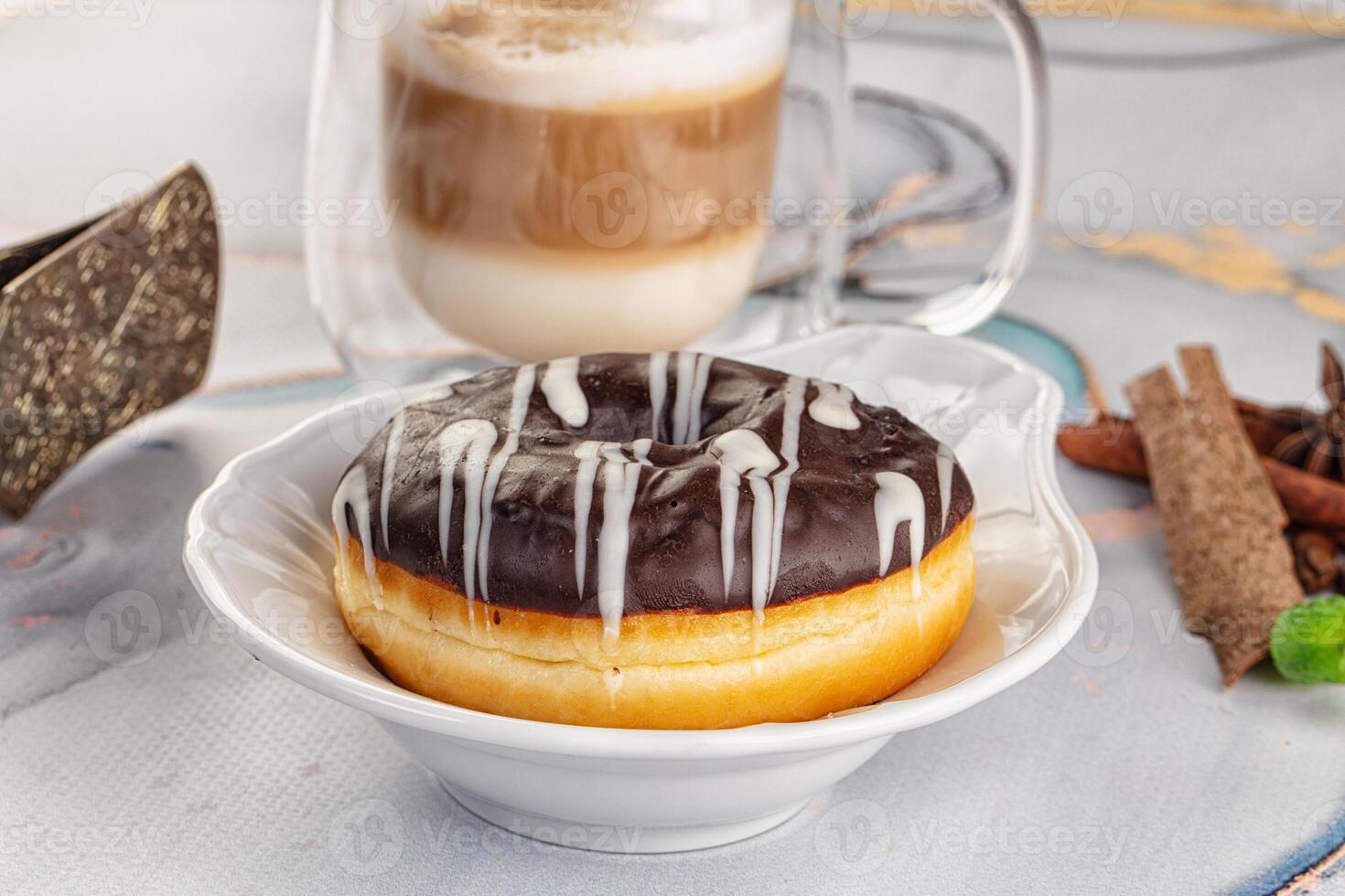 A donut with icing and a cup of coffee photo
