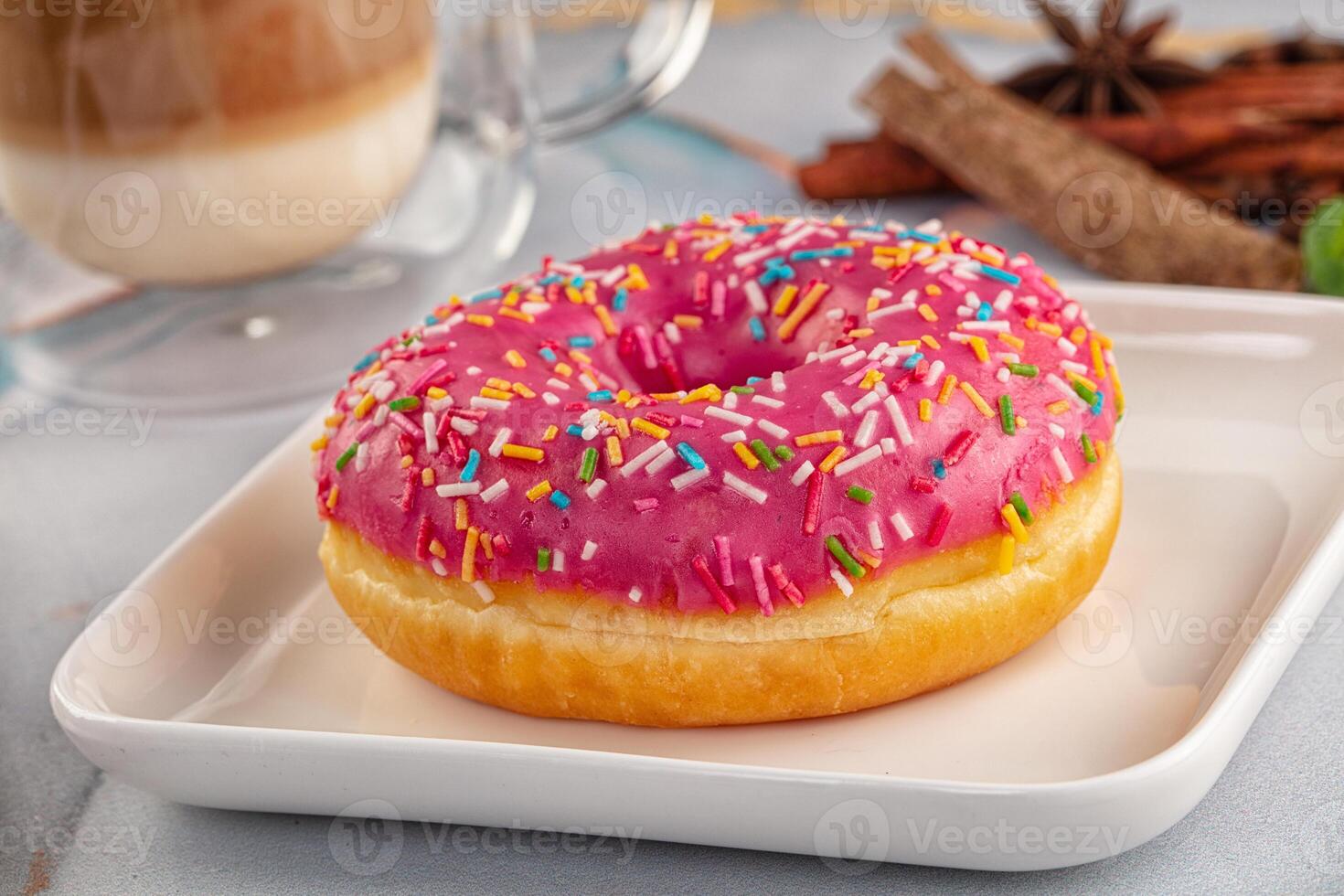 A donut with pink icing and sprinkles on a plate photo