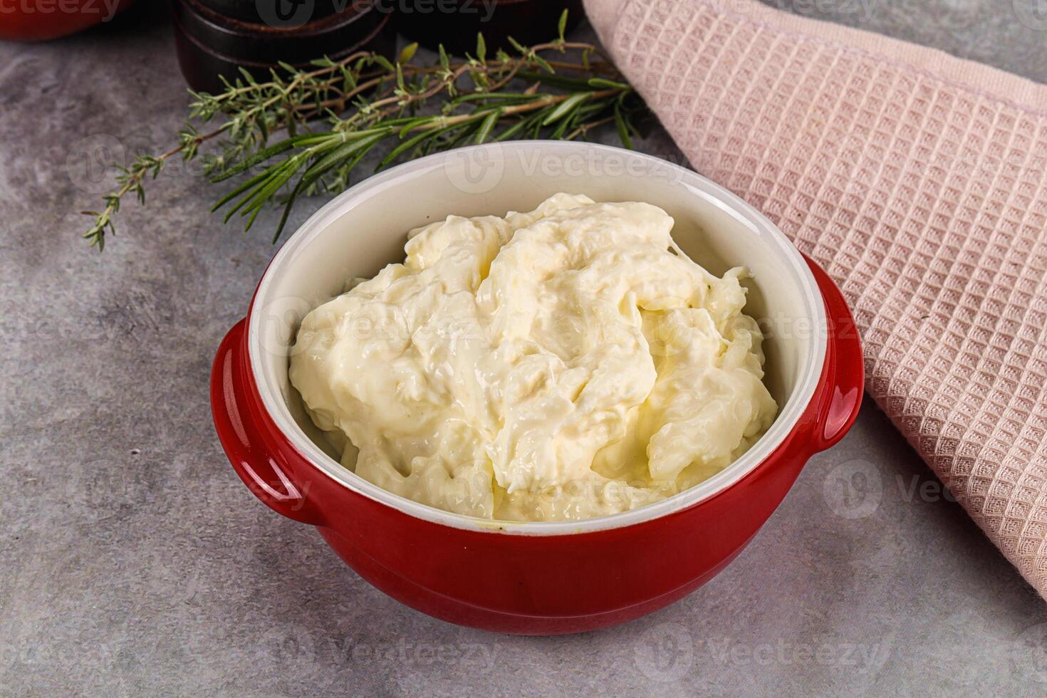 A bowl of cream cheese next to a red dish photo