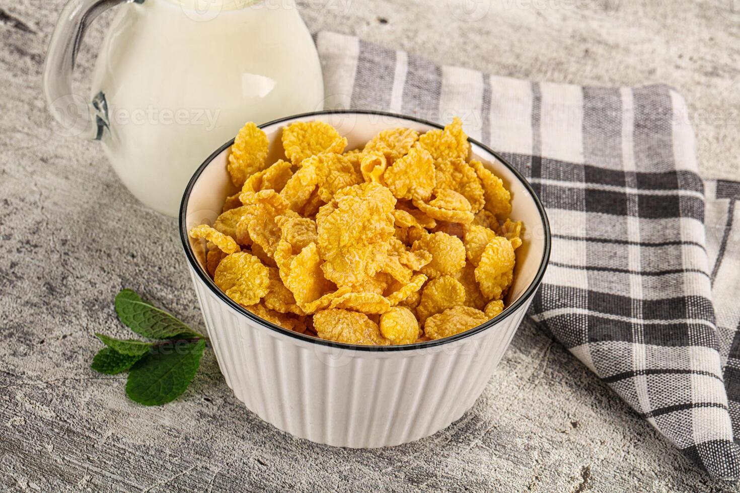 Corn flakes in a bowl and a glass of milk on a wooden table photo