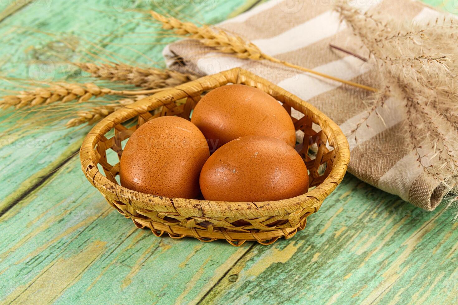 Three eggs in a basket on a wooden table photo