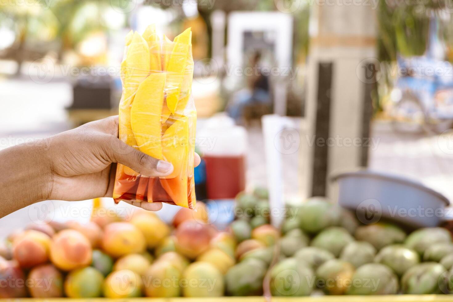 hands of an unrecognizable person holding a bag filled with pieces of ripe mangoes. photo