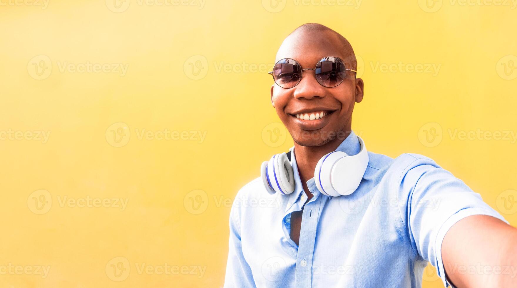 African young man taking a selfie with glasses in front of a colorful wall. photo