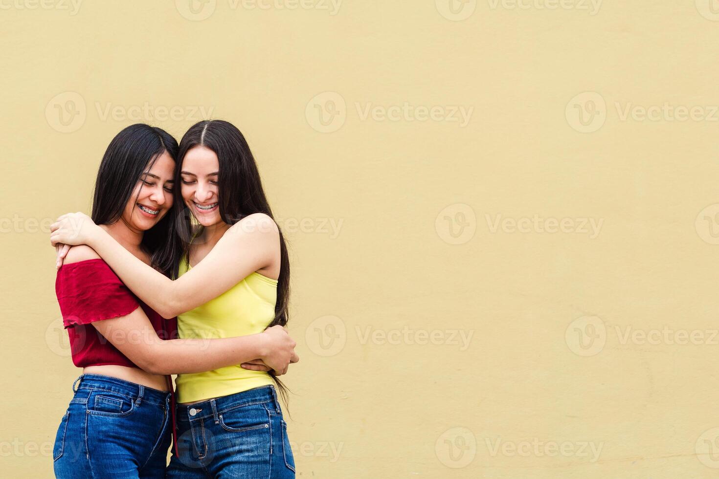 latin americans friends hugging on yellow wall outdoors, happiness concept. photo