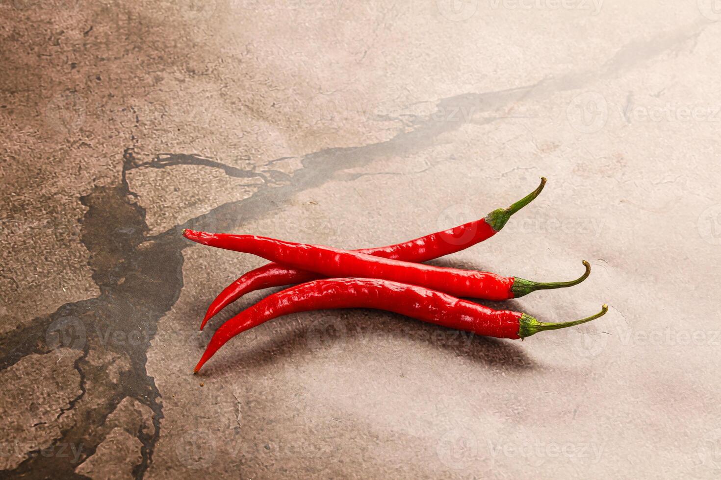 Three red chili peppers on a table photo