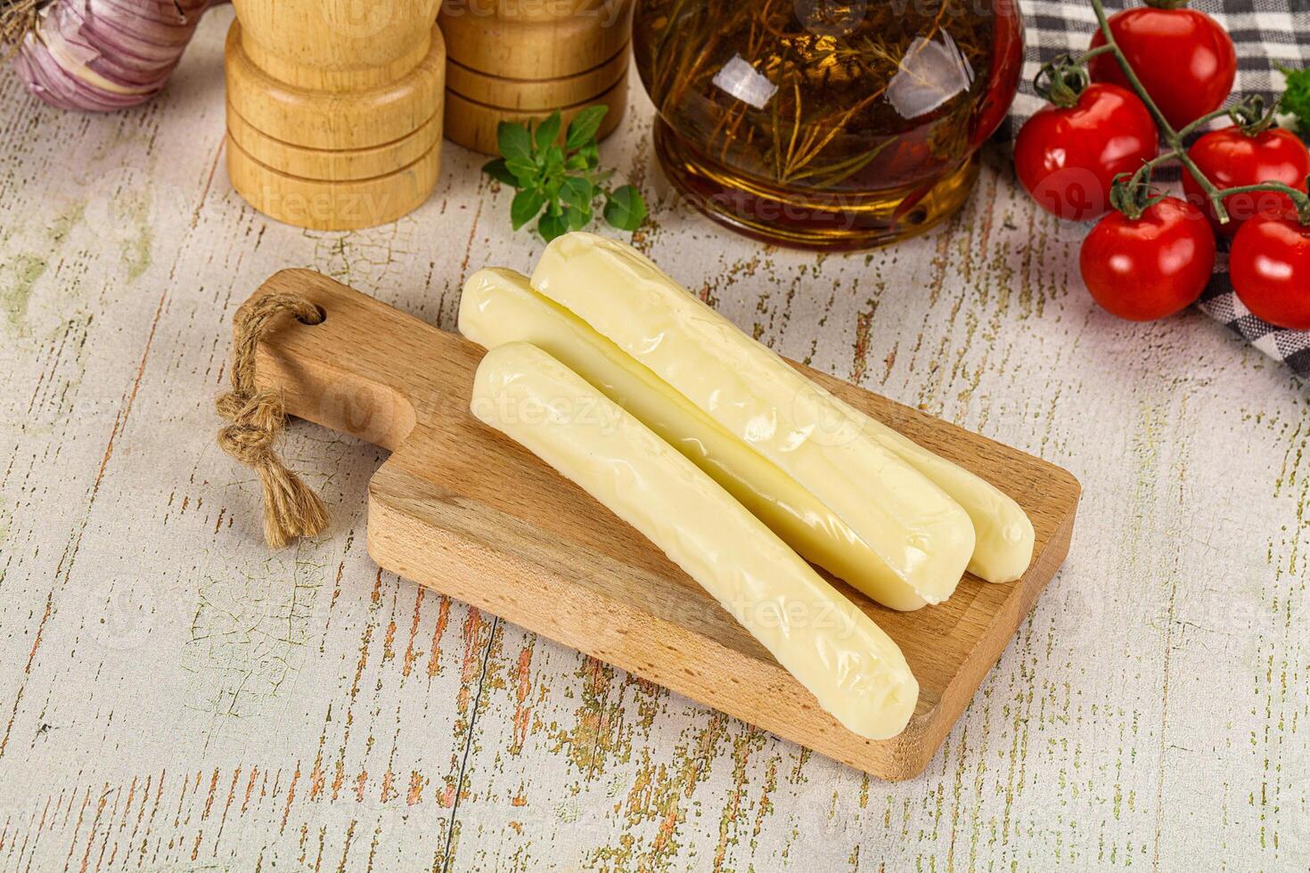 A wooden cutting board with cheese and tomatoes photo
