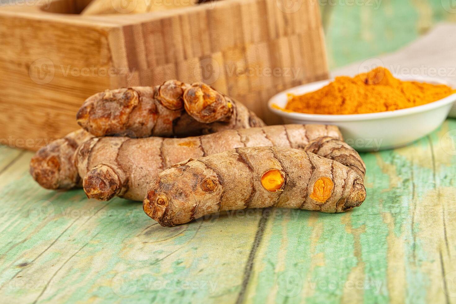 Turmeric root and turmeric powder on wooden table photo