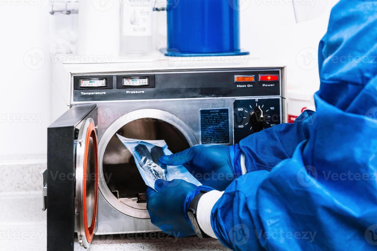 unrecognizable person in bio security suit holding tools and putting them into a machine to sterilize them. photo