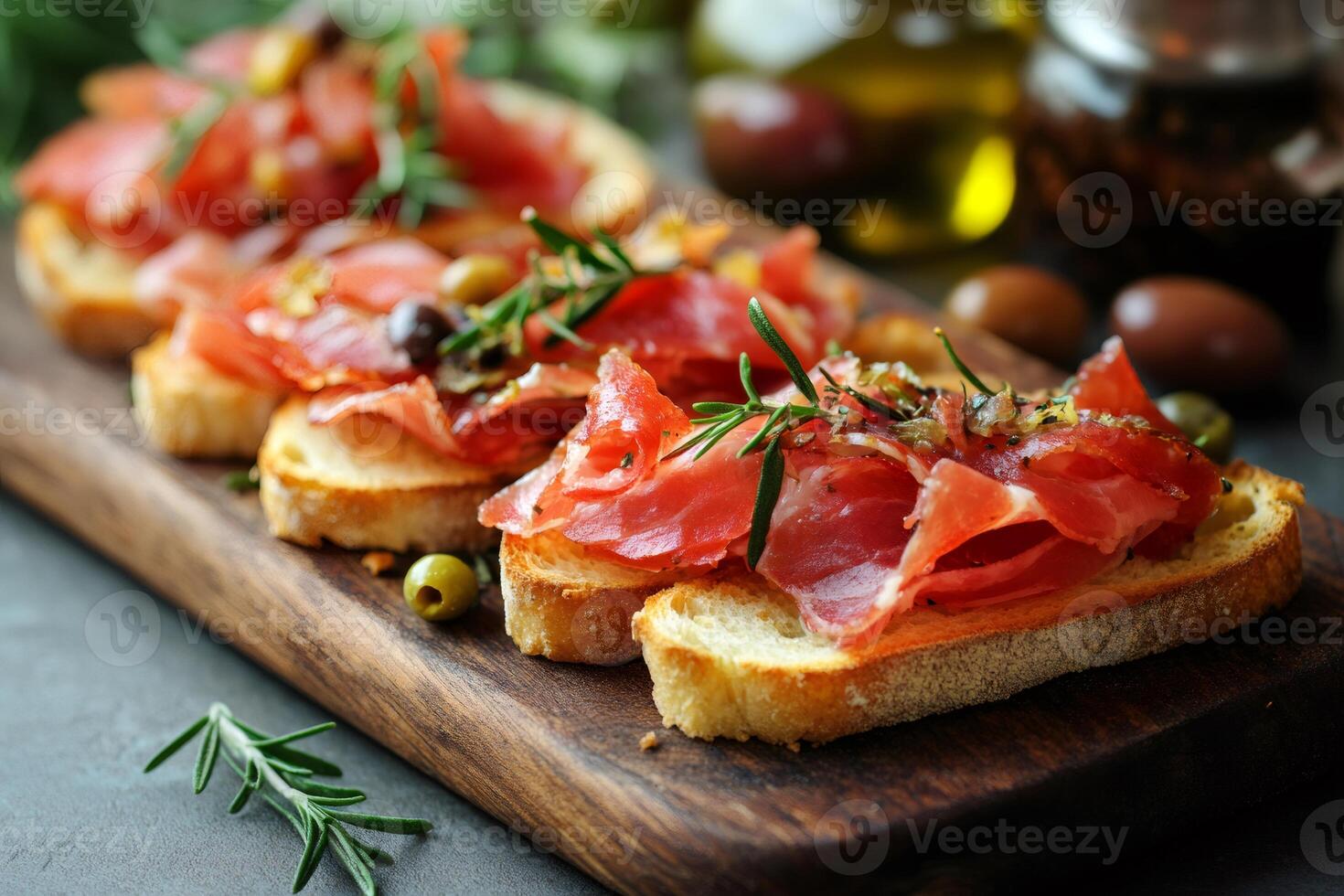 Delicious tapas with iberian ham, topped with rosemary and olives, laying on wooden board photo