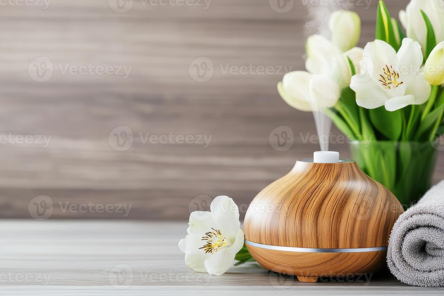 Aroma oil diffuser releasing calming steam into air with spring flowers. .. photo